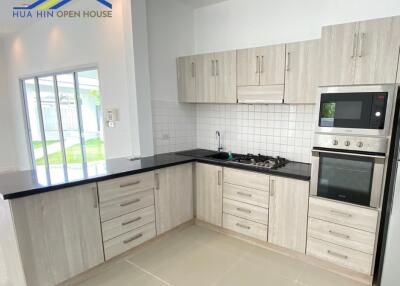 Modern kitchen with white cabinets, black countertops, and stainless steel appliances