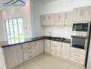 Modern kitchen with white cabinets, black countertops, and stainless steel appliances