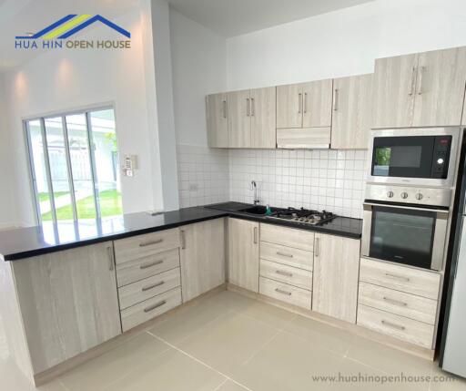 Modern kitchen with white cabinets, black countertops, and stainless steel appliances