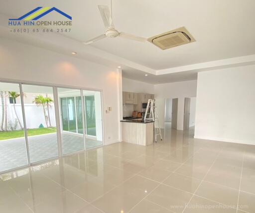 Spacious modern living area with sliding doors to the outside, featuring tiled floors, ceiling fan, and adjacent kitchen.