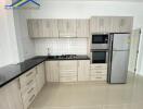 Modern kitchen with wooden cabinets, black countertops, and stainless steel appliances.