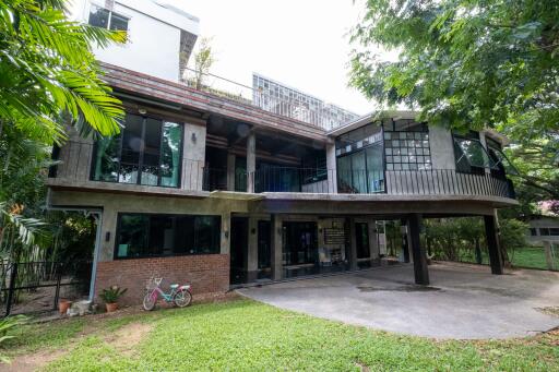 Exterior view of a modern multi-story house with large windows and greenery