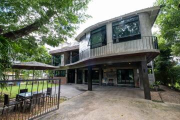 Modern two-story house with large windows and outdoor dining area