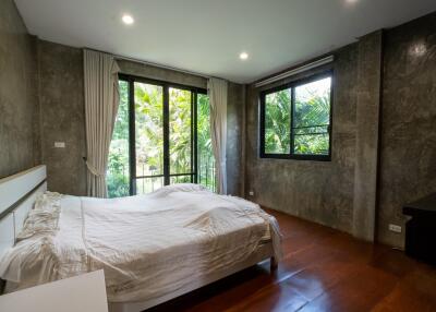 Modern bedroom with large windows and greenery view