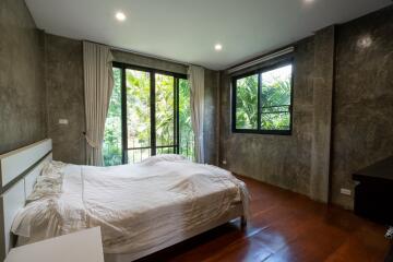 Modern bedroom with large windows and greenery view