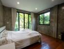 Modern bedroom with large windows and greenery view