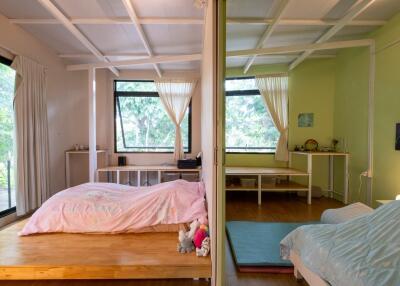 A split view of two cozy bedrooms with large windows, pastel-colored décor, and natural light