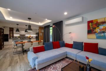 Modern open-plan living room with a large sectional sofa, dining area, and kitchen