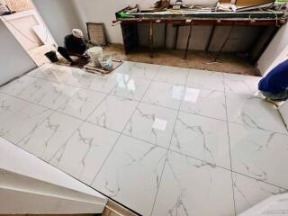 workers installing marble tiles on floor