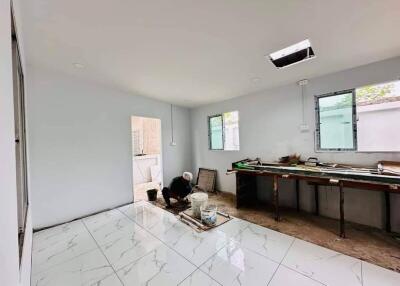 Living area under renovation with worker, white tiled floor, and large windows