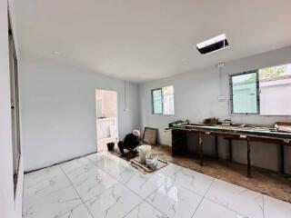 Living area under renovation with worker, white tiled floor, and large windows