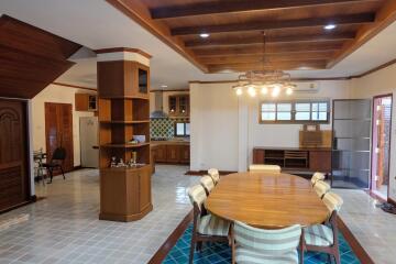 Spacious dining room with wooden table and chairs, connected to a kitchen with modern furnishings.