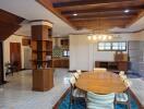 Spacious dining room with wooden table and chairs, connected to a kitchen with modern furnishings.