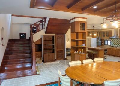 Spacious and well-lit living area with dining table, kitchen, and staircase