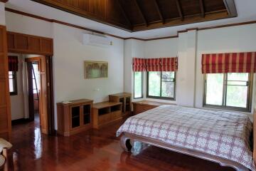 Spacious master bedroom with wooden furniture and large windows