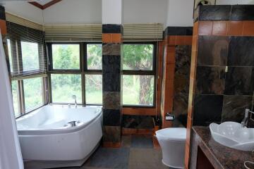 Spacious bathroom with large windows, corner bathtub, and modern fixtures