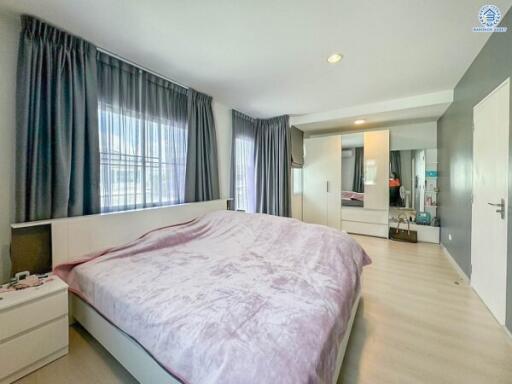 Spacious bedroom with large bed, mirrored wardrobe, and ample natural light