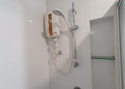 Bathroom shower area with white tiles and shower equipment