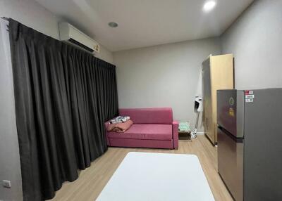 Modern living room with a pink sofa, air conditioner, curtain, and a refrigerator