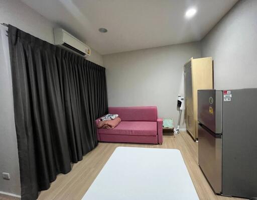 Modern living room with a pink sofa, air conditioner, curtain, and a refrigerator