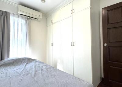 Bedroom with large window, air conditioner, and built-in wardrobe