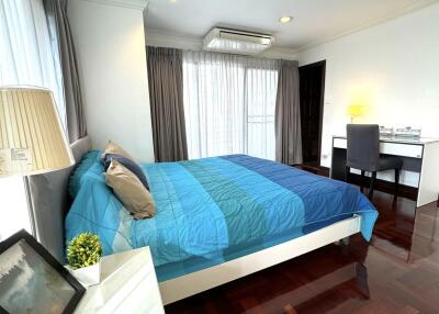 Bedroom with a blue bedspread, white furniture, and dark wood flooring