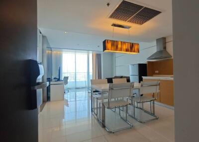 Modern dining area with white chairs and a large window, view extends to partial kitchen