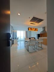 Modern dining area with white chairs and a large window, view extends to partial kitchen