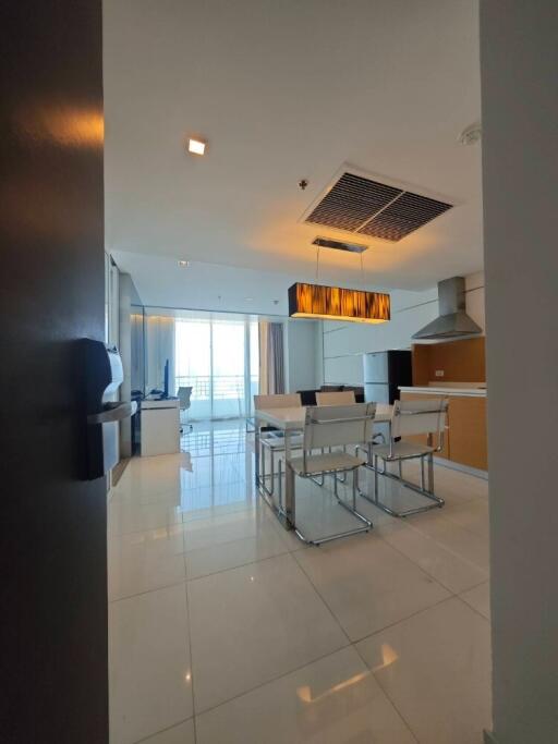 Modern dining area with white chairs and a large window, view extends to partial kitchen