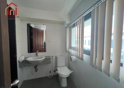 Modern bathroom with sink, toilet, and large window with blinds