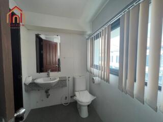 Modern bathroom with sink, toilet, and large window with blinds