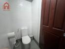 Small bathroom with toilet and wooden door