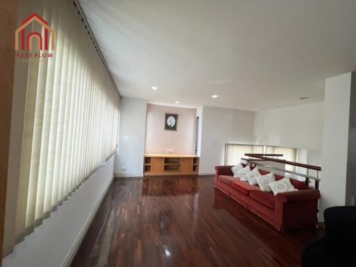 Spacious living room with wooden flooring and a red couch