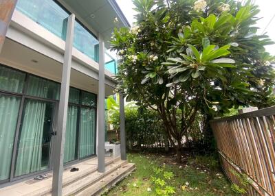 Exterior view of a building with glass balcony and lush garden