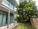 Exterior view of a building with glass balcony and lush garden