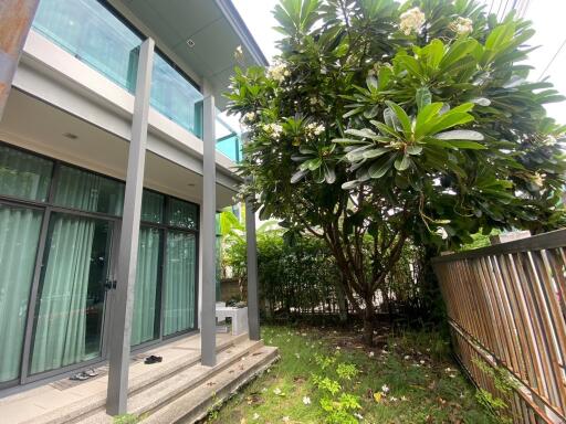 Exterior view of a building with glass balcony and lush garden