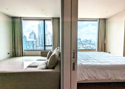 Modern bedroom and partially separated living area with large windows and city view