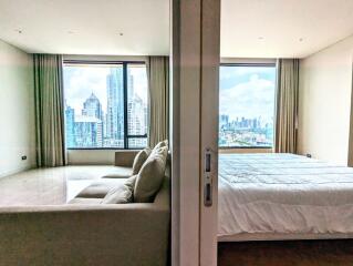 Modern bedroom and partially separated living area with large windows and city view