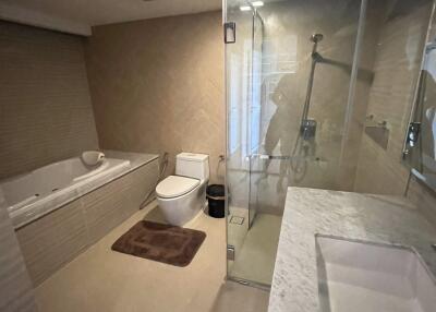 Spacious modern bathroom with glass shower, bathtub, and marble countertop sink.