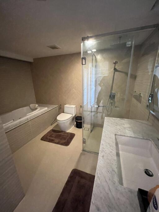 Spacious modern bathroom with glass shower, bathtub, and marble countertop sink.