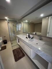 Modern bathroom with glass shower, large vanity, and neutral tones