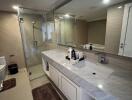 Modern bathroom with glass shower, large vanity, and neutral tones