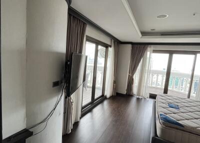 Modern bedroom with large windows, dark hardwood floor, and wall-mounted TV