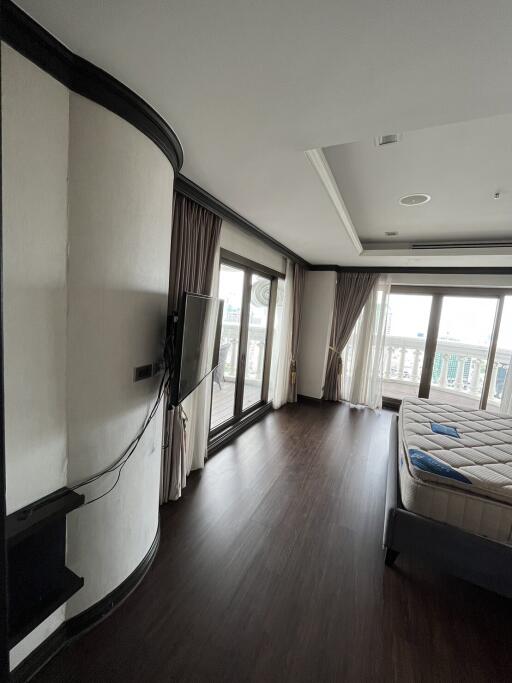 Modern bedroom with large windows, dark hardwood floor, and wall-mounted TV