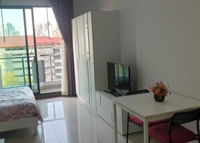 Modern studio apartment with balcony, bed, TV, dining table, and wardrobe