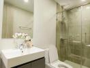 Modern bathroom with white sink, toilet, and glass shower enclosure