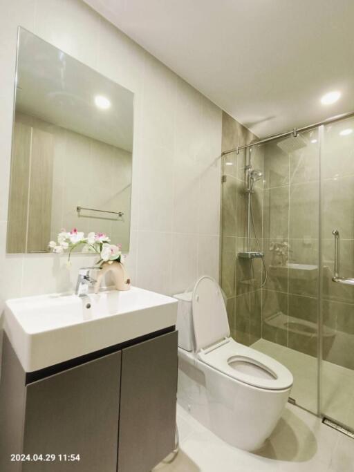 Modern bathroom with white sink, toilet, and glass shower enclosure