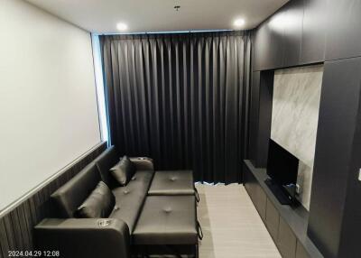Modern living room with a dark gray sofa, wall-mounted TV, and stylish decor