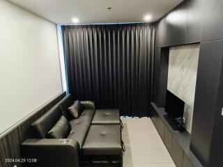 Modern living room with a dark gray sofa, wall-mounted TV, and stylish decor