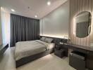 Modern bedroom with double bed, nightstands, and a vanity under warm lighting.